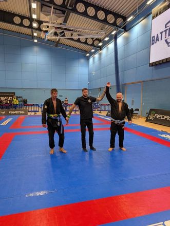 Arbitrul ridică mâna câștigătorului la o competiție de BJJ
